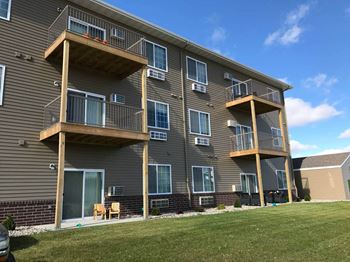 a building with three balconies and a grassy area in front of it at Courtyard Apartments, Minnesota
